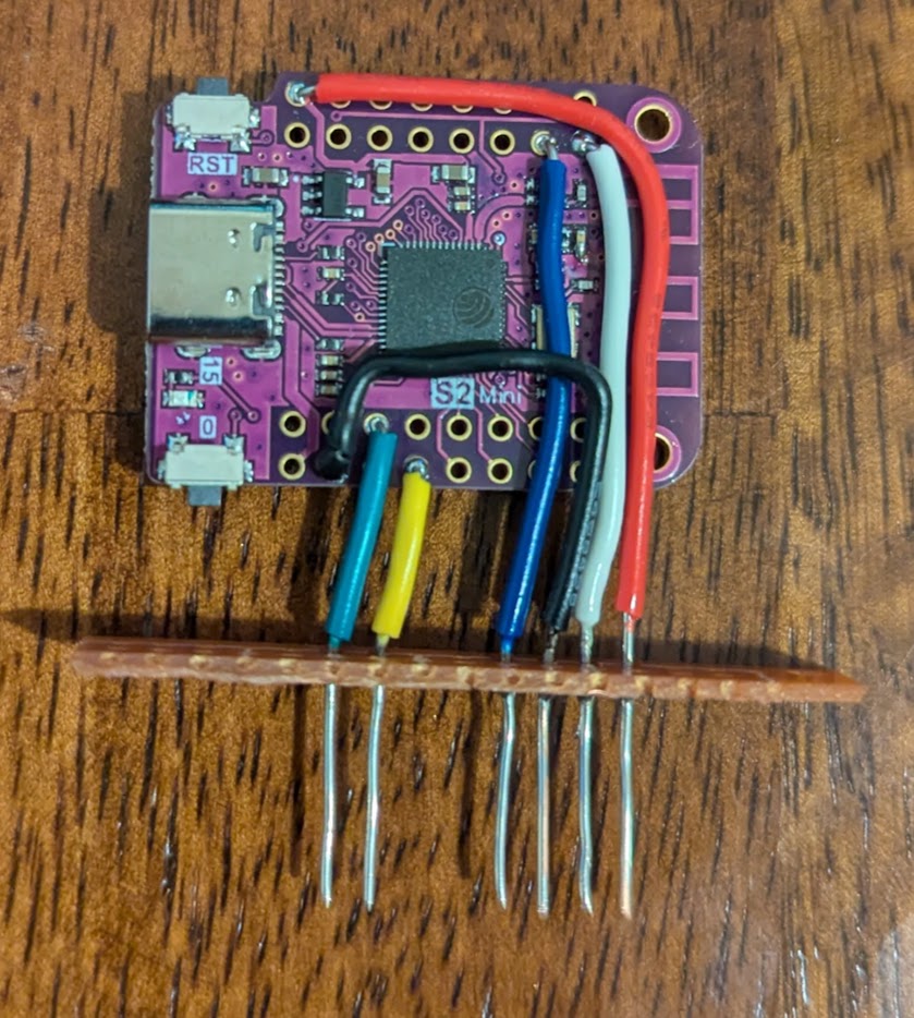 a janky (if you want to be negative) or mad-max-looking (if you want to be positive) ESP32-S2 mini board with wires soldered to it and running through a cracked off piece of perf board to act as header pins for the Flipper