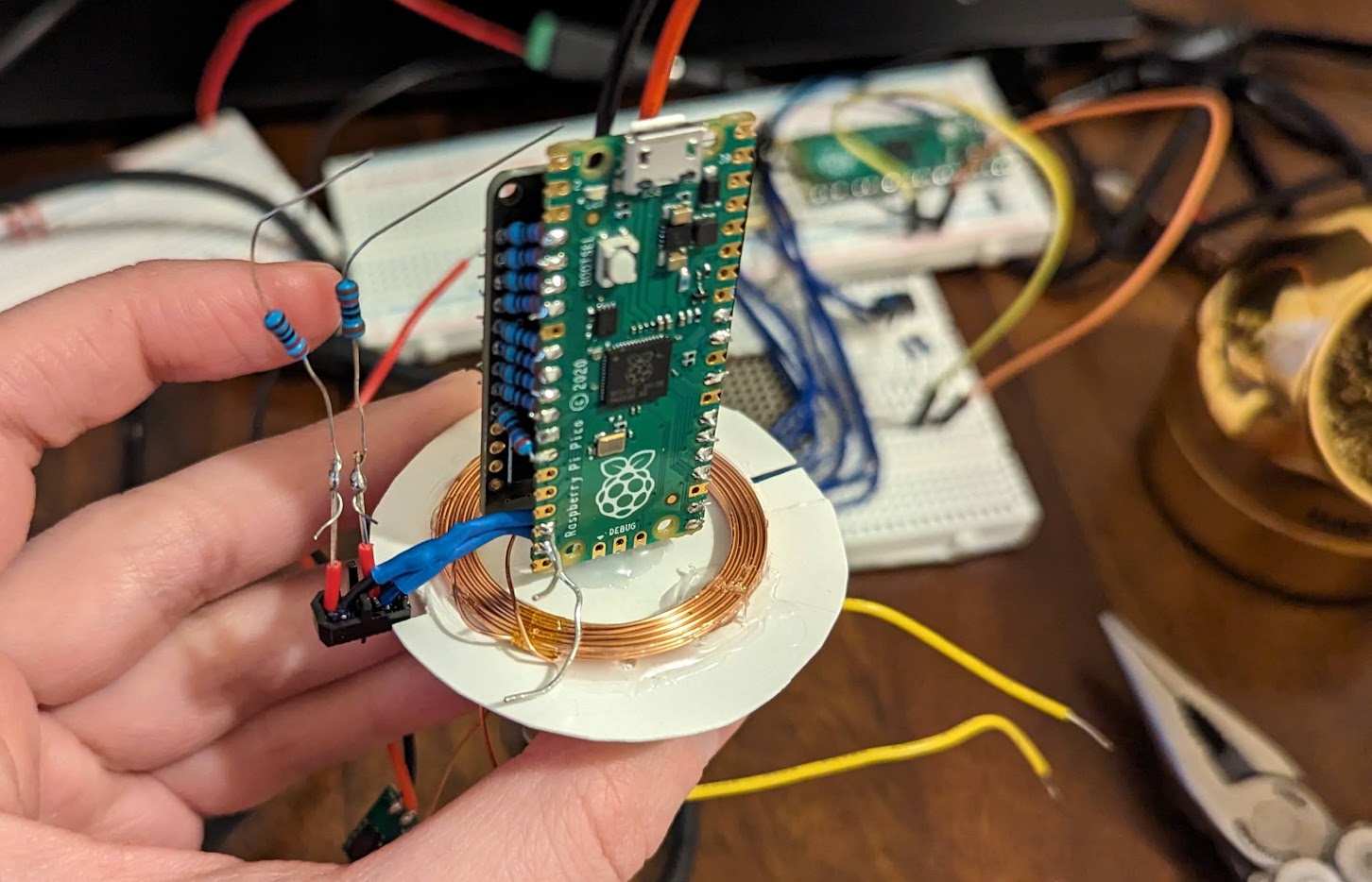 &ldquo;The mostly assembled thing. The pico/LED sandwich is sticking up off of a round white piece of card with the charging coil glued onto it. There are some resistors and wires sticking out.&rdquo;